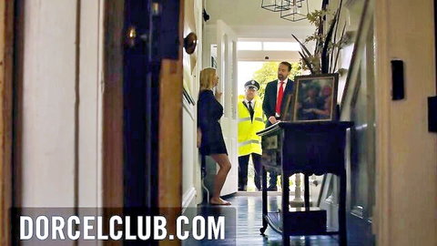 Blonde MILF in tight skirt suit stands seductively with suited man and hi-vis cop in elegant hallway