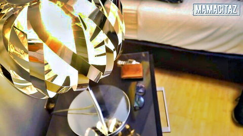 Shiny metallic lamp on nightstand with wallet and sunglasses beside bed