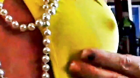 Man's hand gropes busty woman's erect nipple through tight yellow top with pearl necklace