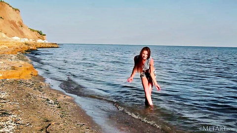 Redhead babe in skimpy bikini wading in ocean waves at sunny beach