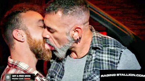 Two hairy muscular bearded men passionately French kissing with tongues visible