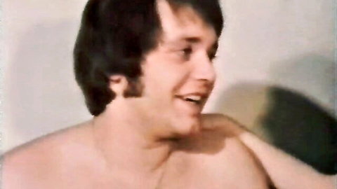 Shirtless retro hunk with hairy chest smiling seductively in vintage bedroom scene