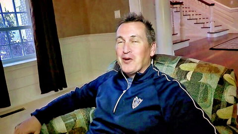 Middle-aged man in blue tracksuit sitting and speaking in chair