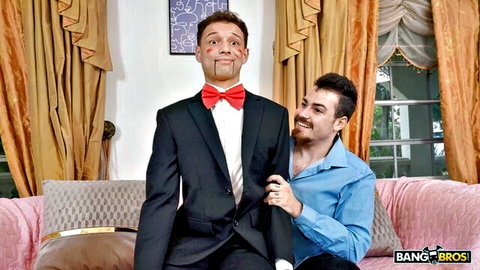 Handsome man in blue shirt poses intimately with dummy-suited guy on pink couch Bang Bros