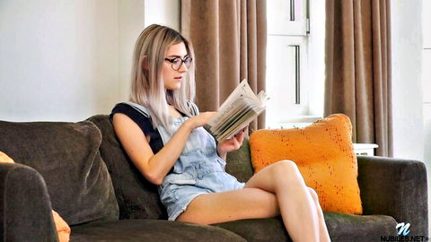 Sensual blonde with glasses and big natural tits reading book on couch in tight overalls