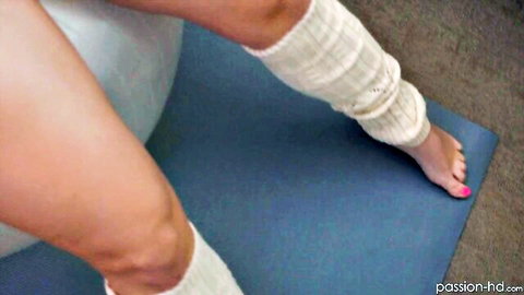 Toned babe's bare thighs and pink toenails in white legwarmers stretching on yoga mat