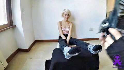 Blonde Kelevra in pink camisole and striped socks, legs extended in POV