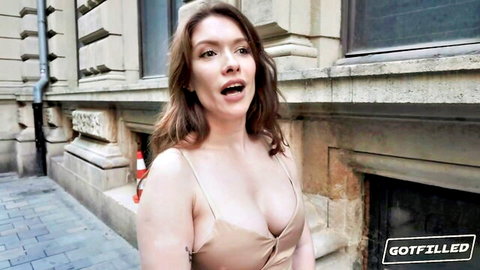 Surprised redhead in tight low-cut dress exposing deep cleavage outdoors