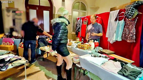 Curvy blonde in short skirt and high heels browsing clothes at public flea market stall