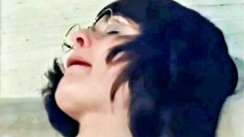 Retro XXX model with glasses, black hair, and nose piercing in vintage adult scene