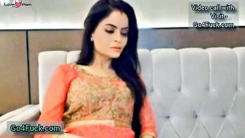 Sexy South Asian Indian wife in embroidered orange blouse sitting on hotel couch teasing