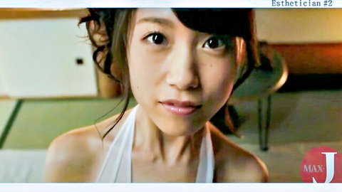 Cute smiling Asian esthetician in tight white tank top teasing cleavage for sensual massage