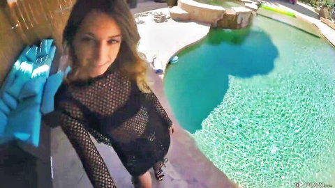 Sexy brunette in sheer black mesh dress posing by turquoise pool