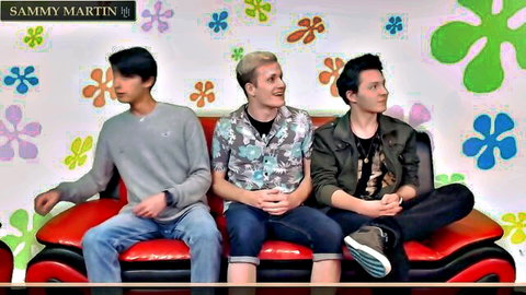 Three smiling guys lounging casually on red couch with SpongeBob flower background