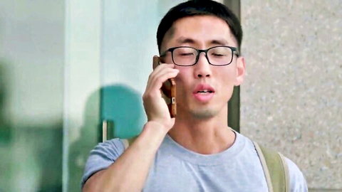 Asian man with glasses on phone, excited expression in light shirt