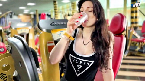 Brunette gym babe with big tits drinks water from cup showing deep cleavage