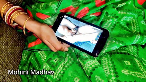 Mohini Madhav in green saree holds phone showing explicit skin close-up