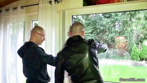 Two bald men in leather jacket and hoodie grabbing roughly by window