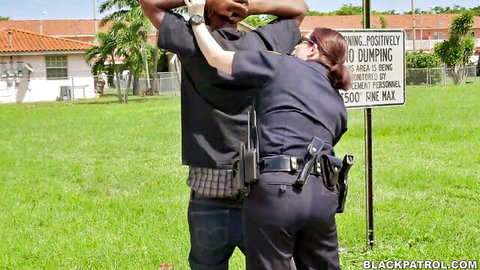 Female cop in uniform arrests black man pushing him against no dumping sign outdoors