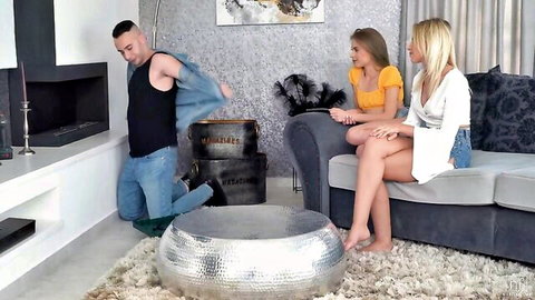 Kneeling guy strips tank top for skinny blonde and brunette on couch threesome tease