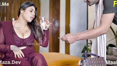 Busty Indian woman in sheer purple top holds drink as man hands her money