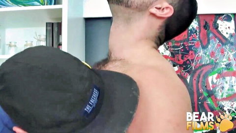 Hairy athletic bear wearing Philadelphia cap exposes muscular shirtless back