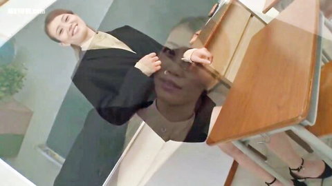 Smiling Asian teacher in suit and stockings, naughty classroom tease