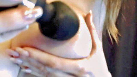 Blonde woman presses black dildo against her exposed nipple and big tit