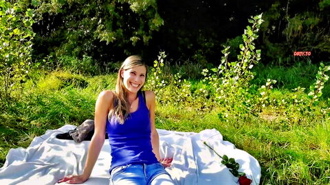 Smiling skinny blonde MILF in tight blue tank top showing small tits on outdoor picnic blanket with dog