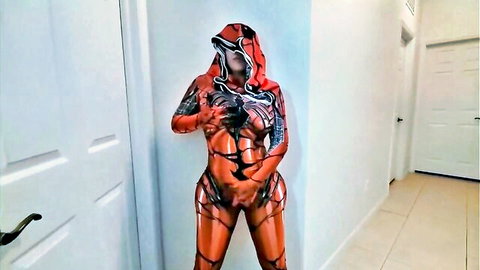 Sexy Venom cosplay babe in shiny orange latex bodysuit flaunting huge ass and big tits in hallway