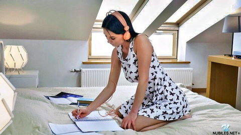 Busty European Simonn in polka dot dress with headphones, sitting on bed