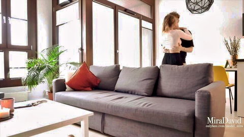 Blonde babe hugs shirtless muscular guy from behind on sofa in romantic tease
