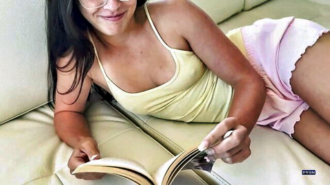 Skinny brunette teen with small tits and glasses reads book in low-cut yellow tank top and pink shorts