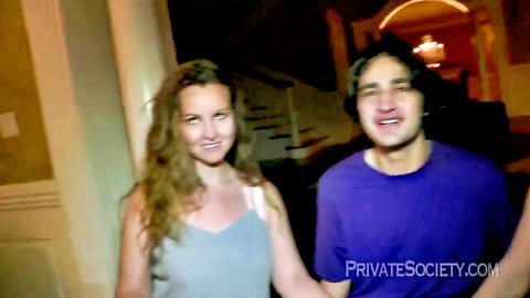 Smiling brunette in tank top with handsome man in purple shirt in luxurious mansion hallway