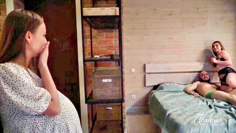 Pregnant wife shocked hand-to-mouth watching husband bulge in green underwear with lingerie woman on bed