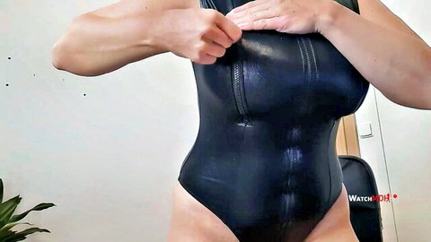 Muscular MILF in shiny black latex bodysuit squeezing her big tits with both hands