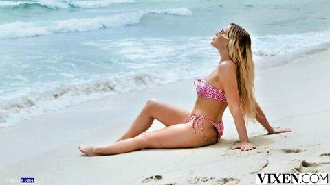 Blonde bombshell in pink bikini lounging on beach showing curvy body huge natural tits