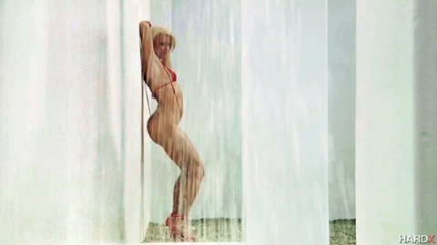 Blonde babe in tiny red bikini poses with juicy wet ass against shower wall