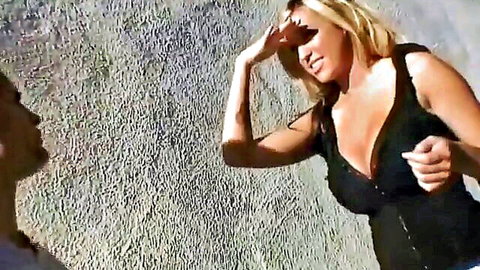 Blonde babe in low-cut black dress shading eyes outdoors, teasing for pounding