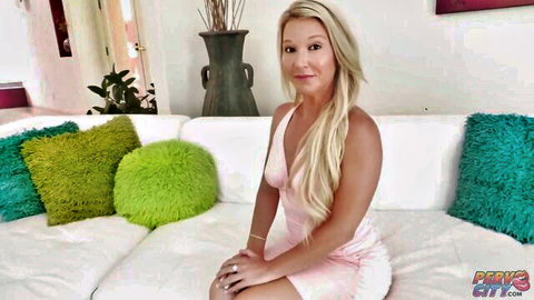 Busty blonde Laura Bentley in sexy pink dress on couch