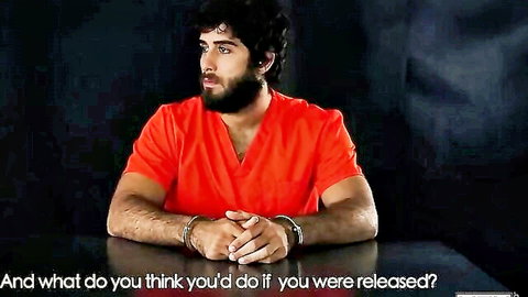 Bearded man in orange prison jumpsuit handcuffed at table, pondering release