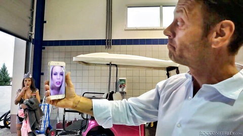 Rocco Siffredi holds phone with sexy babe's face in provocative pose, garage tease