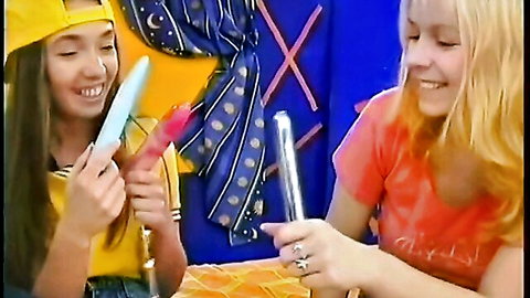 Meri and blonde friend playfully share colorful popsicles in fun scene