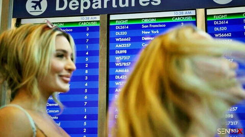 Aiden Ashley and Chloe Rose smiling at airport departures board, mile high club tease