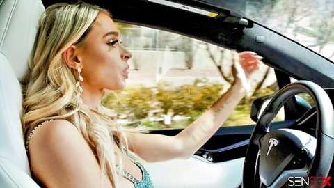 Emma Hix blonde driving Tesla in cleavage-baring dress