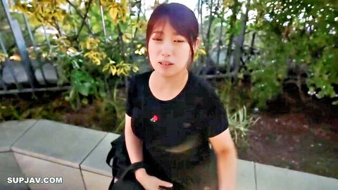 Asian woman in black top squatting outdoors, teasing with soft massive breasts
