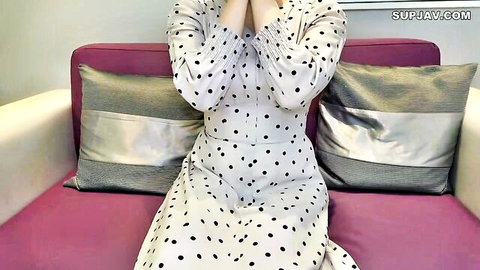 Fair-skinned Asian student in polka-dot dress shyly sitting