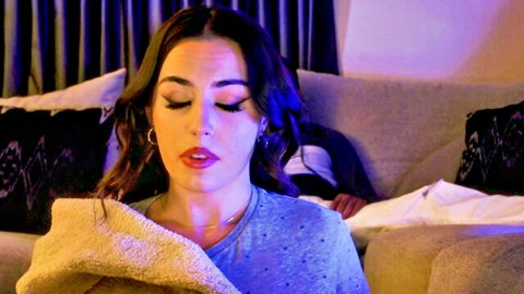 Demi Hawks in blue sweater with Chanel Camryn on couch in dark scream video