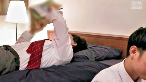 Two suited Asian men lying on bed together, one holding book intimately