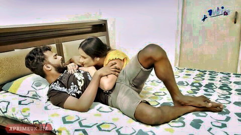 Passionate Indian couple locked in steamy tongue kiss on bed, her hand gripping his chest intimately.
